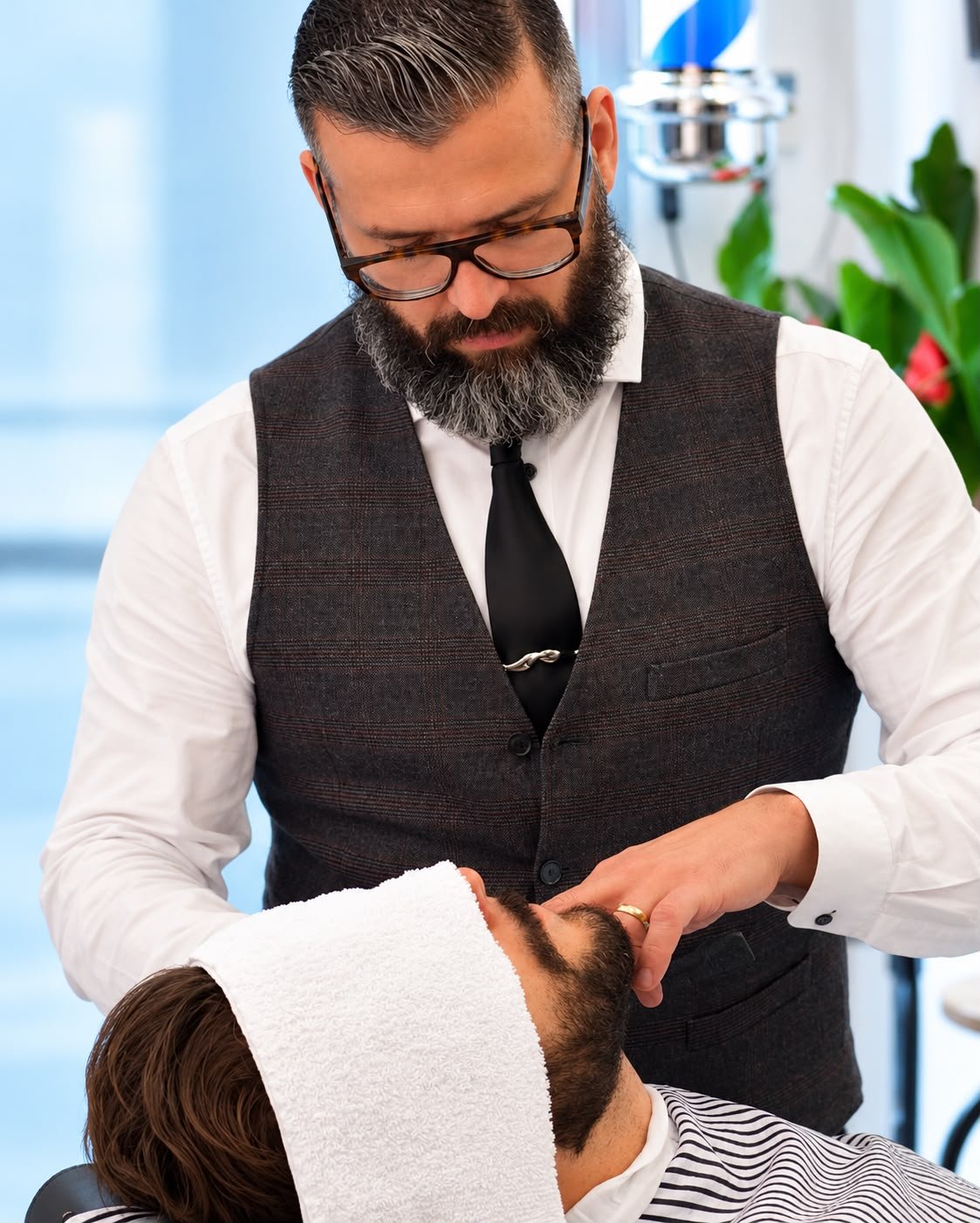 Roi atendiendo a un cliente durante un afeitado clásico en su barbería de Hospitalet, junto a Barcelona